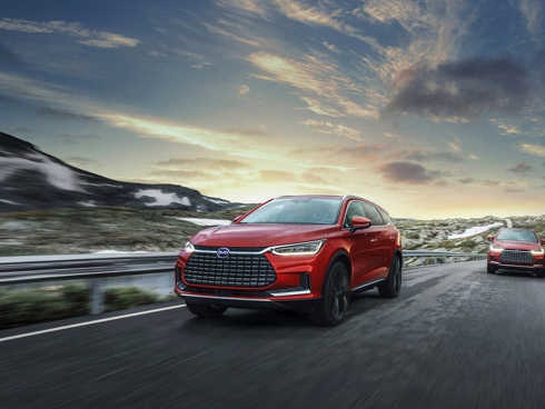 To røde elektriske BYD biler kører på en vej